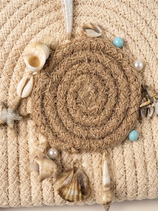Decorative wall hanging with seashells and pearls on a textured beige background
